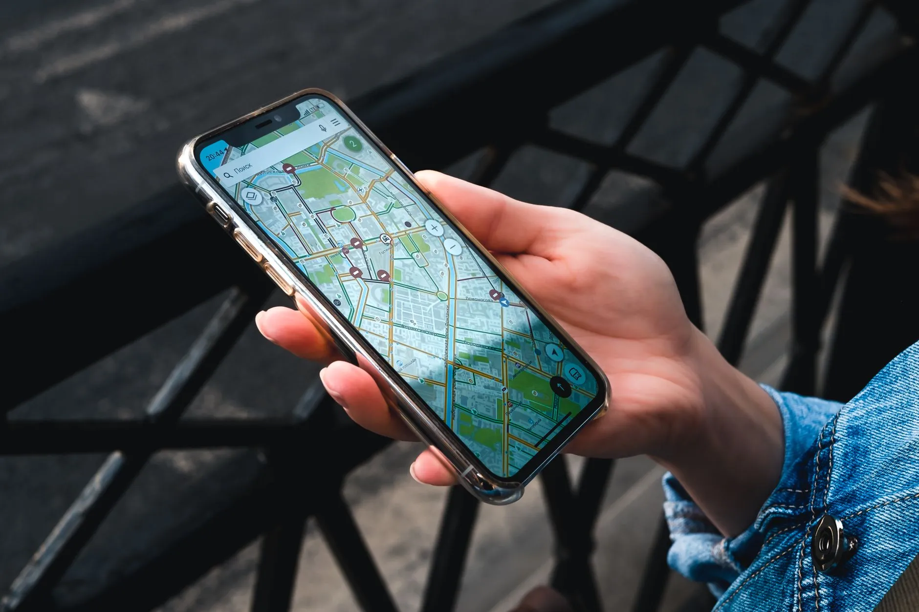 Hand holding a smartphone displaying a map app on an outdoor street